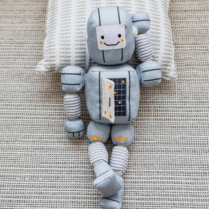 Description: Meet the TOT BOT from WONDER AND WISE ASWEETS, an educational toy designed to delight and educate. With its light gray body, segmented arms and legs, and cheerful yellow accents, this plush robot is sure to captivate. The friendly face sports black eyes and a happy smile, while the rectangular torso is adorned with colorful buttons and charming striped patterns on its limbs.