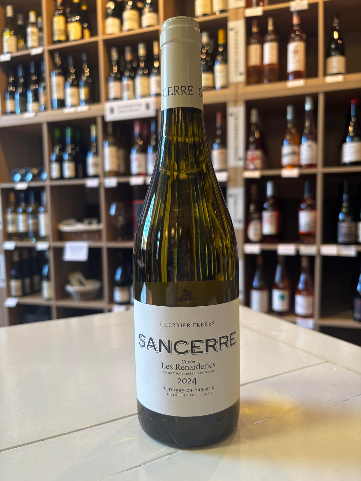 A bottle of CHERRIER FRÈRES &#39;LES RENARDERIES&#39; SANCERRE 2024 from WINE: KELLOGG SELECTIONS sits on a white counter, with shelves of Loire Valley wine bottles displayed in the background.