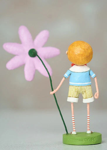 The 7-inch "Billy Bloom" figurine by Lori C. Mitchell for ESC and Company is made of poly resin. It features an orange-haired child in a blue shirt, striped shorts, and socks, joyfully holding a tall pink flower, standing on a green base against a blurred neutral background.