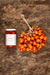 A jar of Italianavera Vesuvielo tomato sauce sits next to a bundle of VESUVIO PIENNOLO TOMATOES from ZIA PIA IMPORTS, tied together with twine on a rustic brown surface.