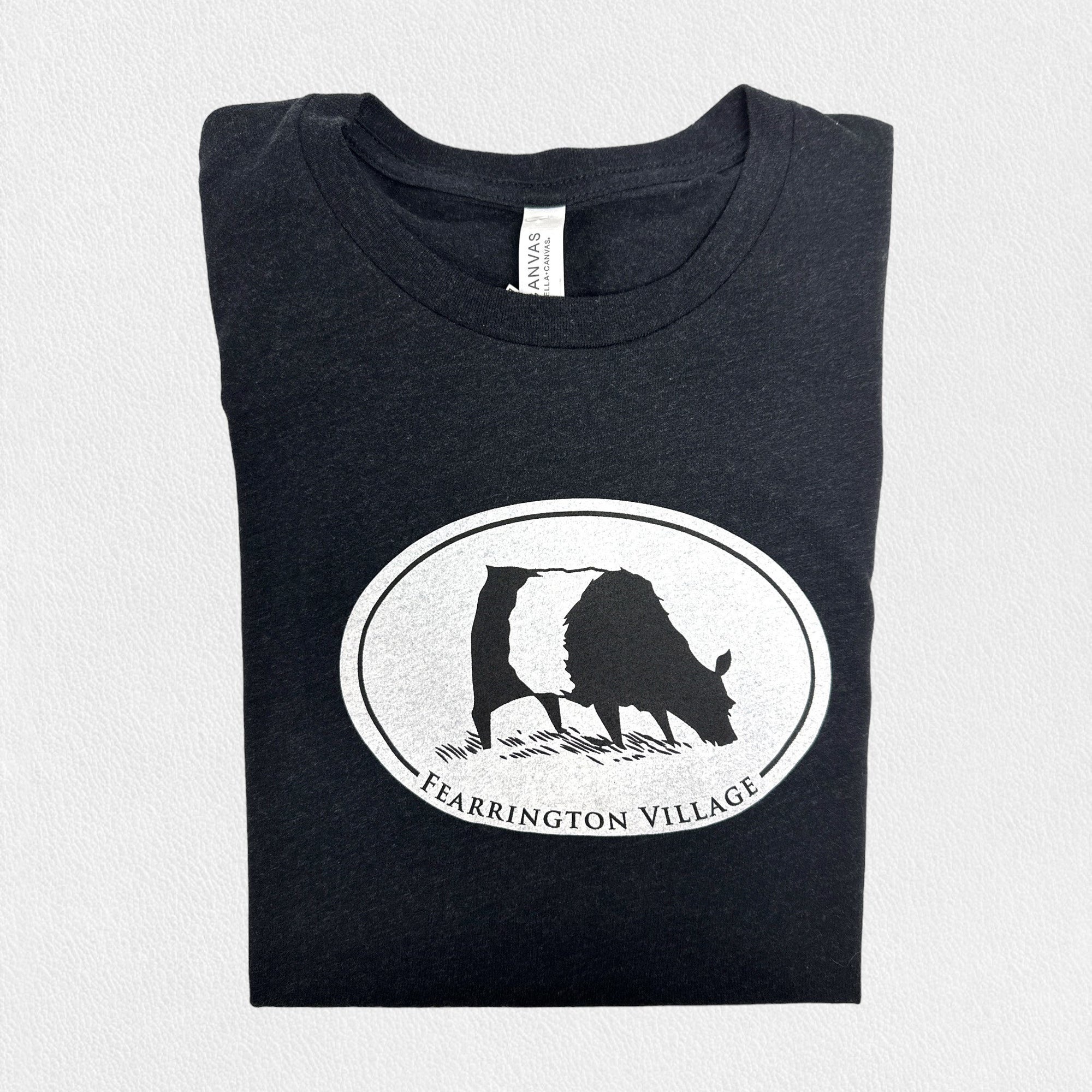 A black triblend unisex tee from the FEARRINGTON LIFESTYLE COLLECTION by GILDAN, showcasing a white oval logo with a silhouette of a goat and the text "FEARRINGTON VILLAGE" underneath, set against a plain light gray background.