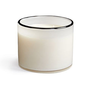 A LAFCO Champagne Penthouse 3 Wick Candle with a black rim burns next to a white vase holding essential oil-infused reed diffusers. A photo of intertwined hands rests in the background, while a box labeled "LAFCO" and wick trimmers lie nearby.