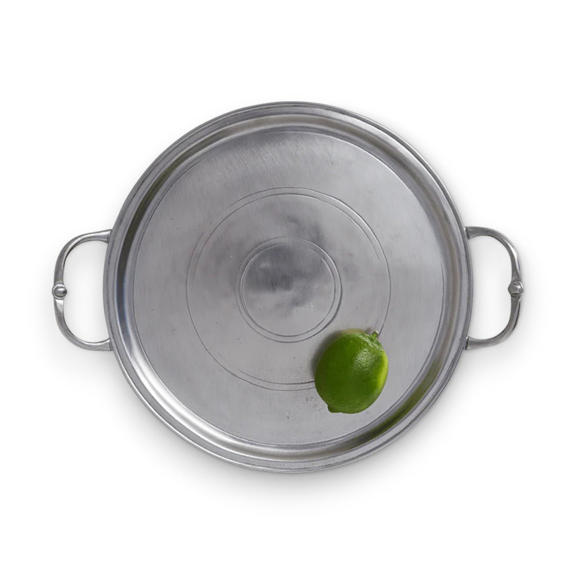 A whole lime sits on the MATCH - SMALL ROUND TRAY WITH HANDLES by MATCH, seen from above on a white background.