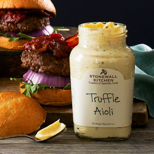 The STONEWALL KITCHEN-TRUFFLE AIOLI is showcased in a jar, with a label highlighting its gluten-free and non-GMO attributes. The net weight is 291g (10.25 oz). This gourmet condiment comes with a green lid, and the label displays text mainly in green and black on a white background.