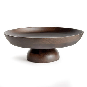 The BOWIE FOOTED BOWL by NAPA HOME AND GARDEN stands against a plain white background. Crafted from dark brown mango wood, its wide, shallow basin features smooth, curved edges and a polished finish that highlight the contemporary design's craftsmanship. The bowl rests on a solid, rounded base providing stability.