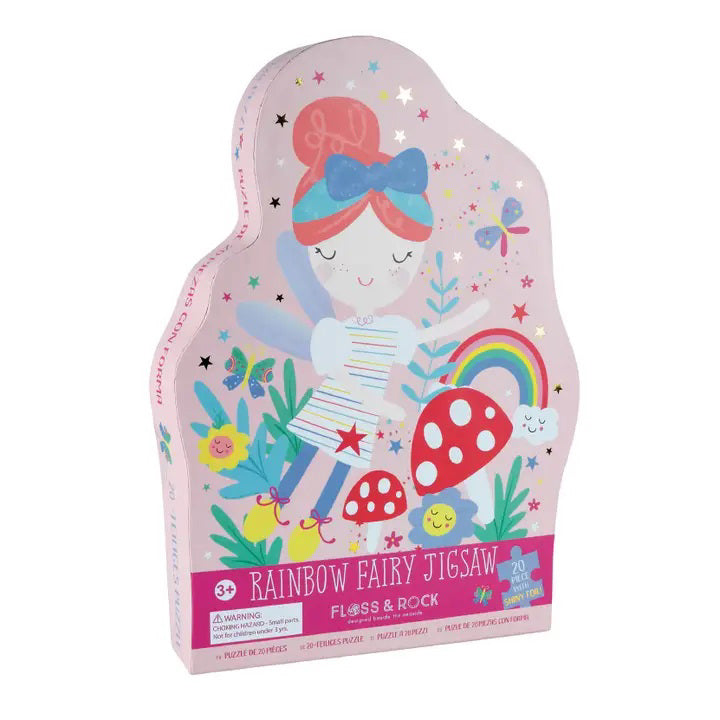 A vibrant, fairy-shaped box contains the 20-piece &quot;FLOSS AND ROCK - RAINBOW FAIRY JIGSAW PUZZLE.&quot; This puzzle by Floss &amp; Rock features a whimsical design with a fairy holding a rainbow, surrounded by flowers, mushrooms, unicorns, a smiling sun, and various playful elements. The brightly colored pieces make it an ideal choice for children ages 3 and up.