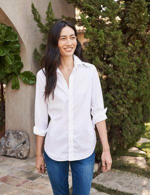 A FRANK AND EILEEN - FRANK CLASSIC BUTTON-UP SHIRT SUPERFINE POPLIN in white, featuring a classically tailored long-sleeve design with rolled-up sleeves, is displayed against a plain, textured background. The label inside the collar reads "FRANK & EILEEN." This shirt offers a classic, slightly relaxed fit with a curved hemline and bust-flattering button placement.