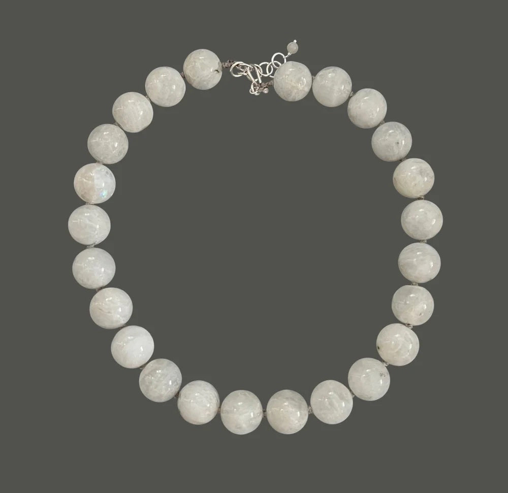 The ANN LIGHTFOOT - WHITE MOONSTONE RAS DU COU NECKLACE features smooth, large white moonstone beads and a sterling silver clasp, arranged in a circle on a white background.
