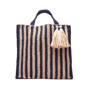 The MAR Y SOL - AMALFI TOTE BAG by MAR Y SOL is a yellow and white striped woven bag with two short handles and a large beige tassel near the top. It features a rectangular shape and textured fabric, offering a chic silhouette that exudes a handcrafted look.