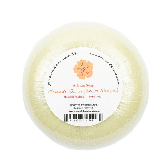 A round, wrapped bar of BAUDELAIRE - SWEET ALMOND 7OZ BOXED BATH BAR with a weight of 200 grams (7 ounces). The label features text in both French and English, along with an orange flower graphic. Made in France and enriched with shea butter, it is imported by Baudelaire, Swanzey, NH.