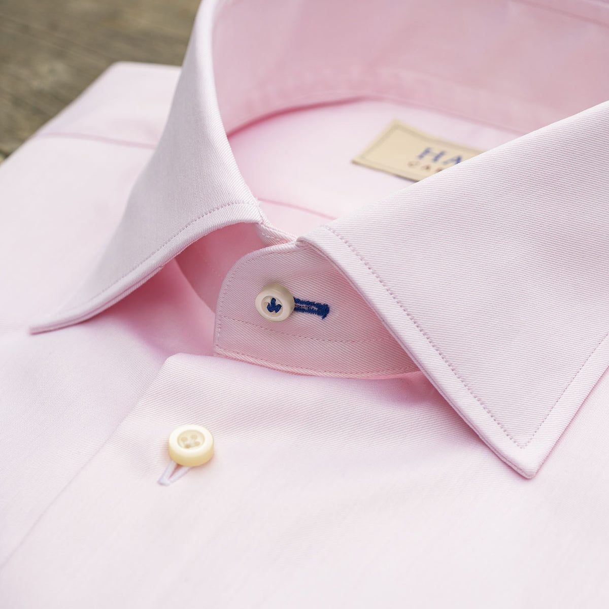 The HAGEN - COTTON DRESS SHIRT IN LIGHT PINK features premium cotton, a modern spread collar with a &quot;Hagen&quot; label, white buttons, and a classic single cuff.