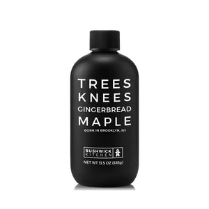 A black bottle of BUSHWICK KITCHEN - 'TREES KNEES' GINGERBREAD MAPLE SYRUP. The text on the bottle includes the product name and weight (13.5 oz / 383g) and notes that it is "Born in Brooklyn, NY." With a black cap and white lettering, it makes for a perfect addition to any Maple Gift Set.