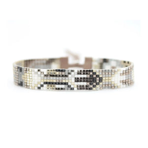 Introducing the JULIE ROFMAN - OSLO BRACELET by JULIE ROFMAN JEWELRY: A beaded bracelet that boasts a captivating geometric design in beige, gray, and brown hues. It features a stylish leather strap with a metallic clasp at the centerpiece and an adjustable closure to ensure the perfect fit.