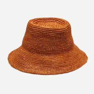 The WYETH HATS - THE TALI is a brown hand-crocheted raffia straw hat featuring a wide brim, showcased against a plain white background.