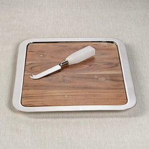 The BRASSERIE STEEL & ACACIA GASTRONOMY BOARD by ZODAX is a rectangular tray featuring a shiny metallic border and a wooden base. The acacia surface shows natural grains and knots, giving it a rustic appearance. With dimensions of 14.25 in x 12.25 in x .75 in, the tray rests on a white background.