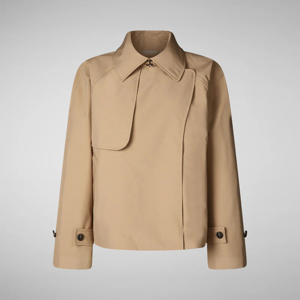 The SAVE THE DUCK - GRETA TRENCH JACKET is a tan trench coat with a wrap-style silhouette, featuring a wide collar, asymmetric flap on the right side, and long sleeves with buttoned cuffs. Its minimalist design stands out against a plain gray background.