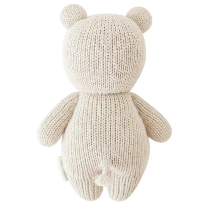 The CUDDLE + KIND - HANDMADE BABY HIPPO by CUDDLE & KIND is a charming, hand-knit stuffed toy featuring a smiling beige hippopotamus with black eyes and small round ears. Its soft, textured appearance and simple, cute features make it an ideal baby shower gift.