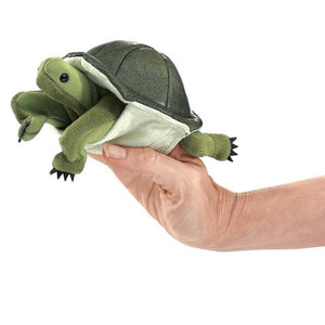 A FOLKMANIS - MINI TURTLE FINGER PUPPET from FOLKMANIS PUPPETS nestled on a person's hand, with its dark shell, light green limbs, and black claws gives a realistic effect. The human hand underneath supports it, making it look like the turtle is ready to play peek-a-boo.