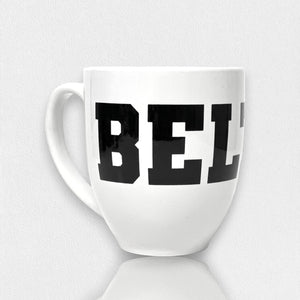 A white FEARRINGTON BELTIE Mug from the FEARRINGTON LIFESTYLE COLLECTION by STRAN, featuring the word "BELI" in bold black capital letters on its side. This mug, ideal for your morning coffee, has a large handle and is showcased on a white surface with a plain white background.