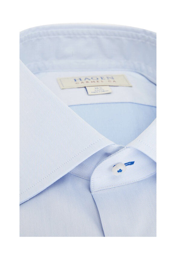 The HAGEN - COTTON DRESS SHIRT IN LIGHT BLUE is neatly folded, featuring a modern spread collar, white buttons, and premium cotton. The label inside the collar displays &quot;Hagen Carmel, CA&quot; with size details.