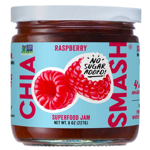 A jar of CHIA SMASH - RASPBERRY CHIA JAM. This 8 oz (227g) jar features a light blue label adorned with images of raspberries and a "NO SUGAR ADDED" text bubble. The label proudly highlights that the product is Non-GMO Project Verified, made with upcycled fruit, and suitable for both paleo and vegan diets.