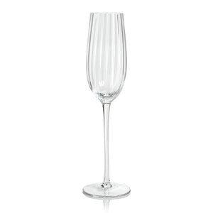 The MADELEINE OPTIC CHAMPAGNE FLUTE by ZODAX is a tall and slender clear crystal glass adorned with vertical grooves extending from the rim to the stem, which rests on a flat, round base. The empty flute showcases a polished, reflective finish that elevates its elegance, making it perfect for special occasions and toasting celebrations.