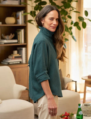 The FRANK & EILEEN's Eileen Relaxed Button-Up Shirt in Washed Linen Forest is displayed in the image. This green, long-sleeve shirt features a front pocket and a relaxed fit with bust-flattering button placement. The sleeves are rolled up to mid-forearm and all buttons are fastened, exuding California effortlessness against a plain white background.