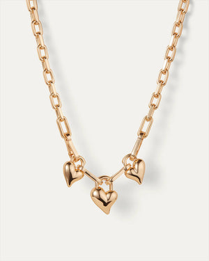 The JENNY BIRD Padlock Triple Heart Pendant Necklace features an elegantly elongated gold-tone dipped brass chain with three removable heart-shaped pendants, each evenly spaced. Its high-polish finish creates a stunning look against a plain white background.