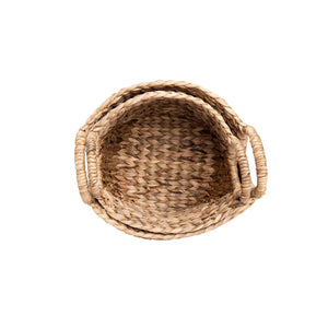 The SEAGRASS BASKET W HANDLES by CREATIVE COOP comprises two round, handwoven seagrass baskets featuring integrated circular handles. These rustic picnic essentials come in slightly varying sizes and are empty. The handles extend upward from the basket's rim, ensuring easy carrying and mobility.