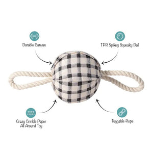 The FRINGE STUDIO - PAINTED GINGHAM PULLING DOG TOY from PET SHOP BY FRINGE STUDIO features a spherical black and white plaid fabric center made of cotton canvas, with two white twisted rope handles extending from opposite sides. Non-toxic inks ensure safety while the TPR spikey squeakerball inside adds an element of fun. The toy is set against a plain white background.