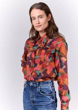 The 0039 ITALY - MIRJAM COTTON PRINT SHIRT by 0039 ITALY is a long-sleeved button-down blouse adorned with a striking abstract floral pattern in shades of red, orange, green, and brown. Crafted from pure cotton, it features a classic collar and a tailored fit that effortlessly combines retro style with modern flair.