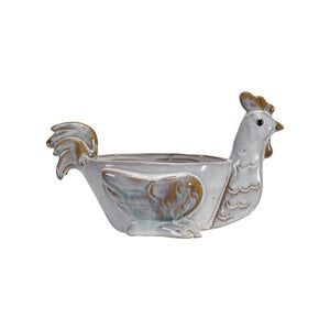 The CREATIVE COOP STONEWARE CHICKEN SHAPED BOWL is a ceramic bowl designed like a chicken with detailed tail, wings, and comb. It has a glossy finish in white and brown due to its reactive glaze, making it perfect as a quirky kitchen sponge holder.