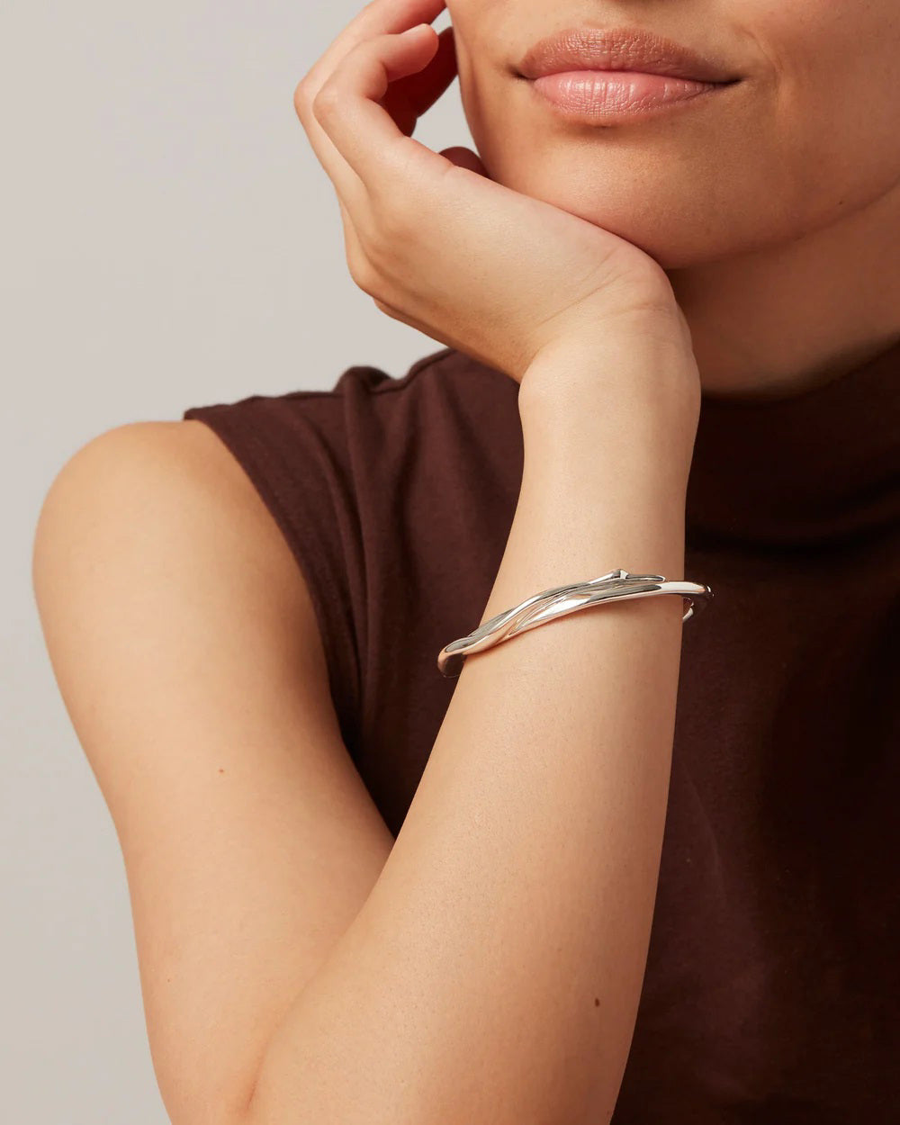 The JENNY BIRD COLETTE BANGLE, a sleek silver accessory with a subtle twist design and high-polish finish, is displayed on a light background.