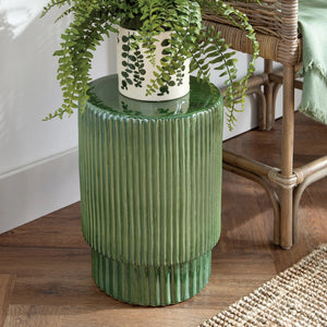 The NAPA HOME AND GARDEN Remi Stool is a green ceramic piece with a ribbed texture and glossy finish, ideal as extra seating or an end table. Its cylindrical shape features a slightly wider top and narrower bottom.