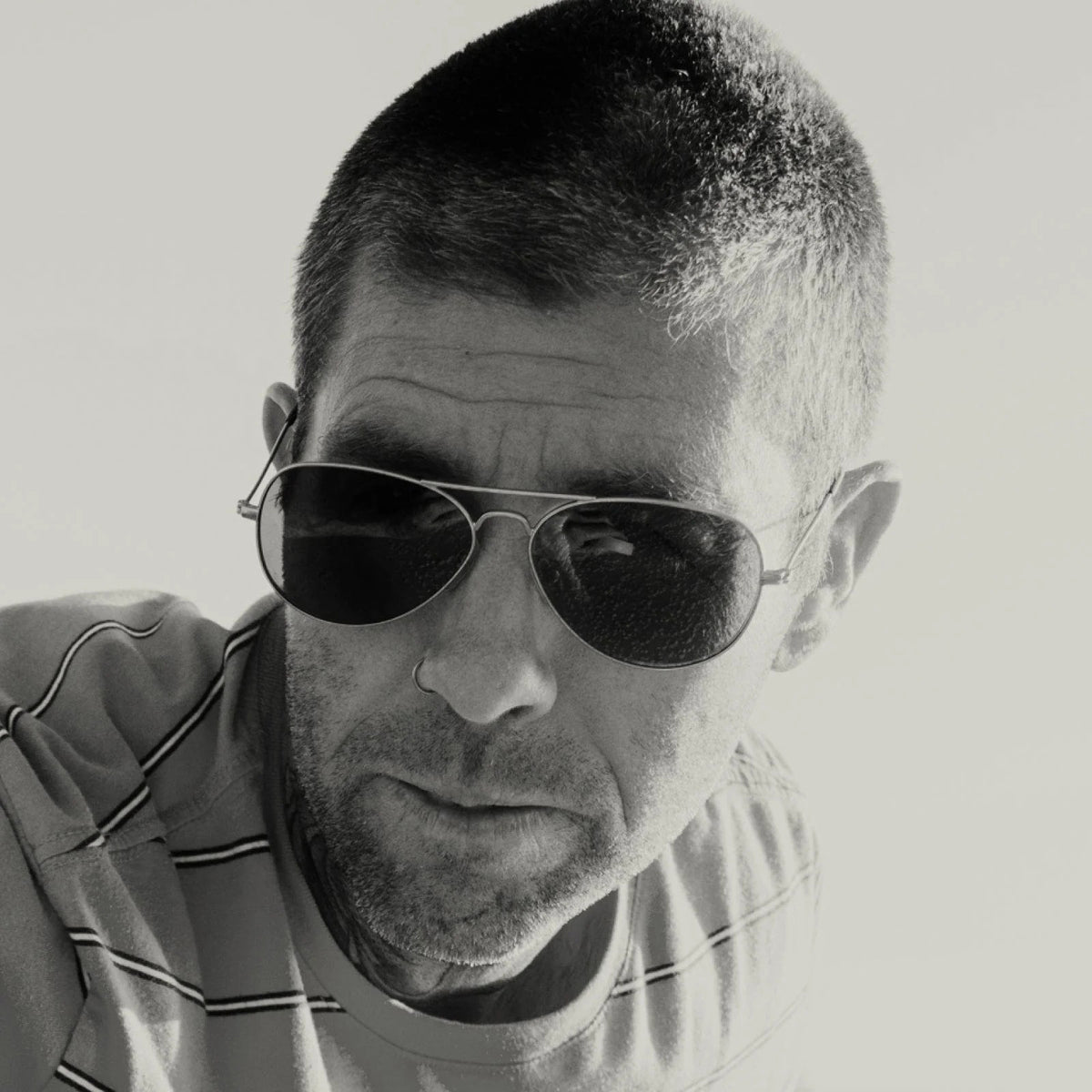 The CADDIS - MABUHAY SUNGLASSES by CADDIS feature a thin gold wire frame, scratch-resistant dark lenses, and brown temple tips, displayed against a white background.