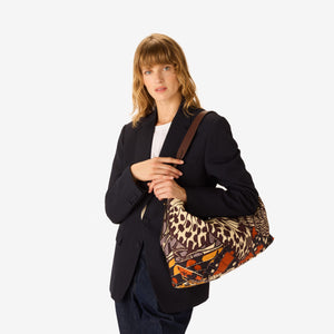 The INOUI EDITIONS MAXI CAMPUS BAG PAPILLON by INOUI is a hobo-style cotton bag with a curved handle, showcasing a vibrant butterfly wing pattern in orange, black, blue, and cream on a plain white background.