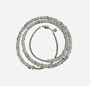 The ANN LIGHTFOOT - TRIPLE WRAP SQUARE CUT LABRADORITE AND PYRITE BRACELET features square and round labradorite beads in a spiral layout with varying transparency for a subtle shimmer, enhanced by a sterling silver clasp for elegance, set against a dark grey background.