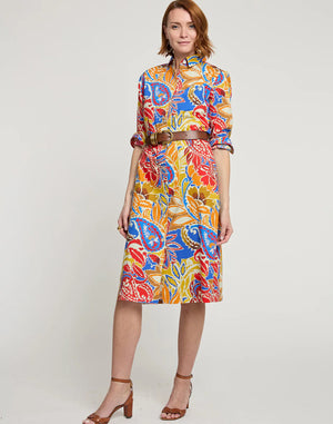 A person with shoulder-length hair is wearing the HINSON WU - TAMRON Long Sleeve Paisley Print Dress with an A-line shape and a brown belt. They are also wearing brown high-heeled sandals and are standing against a plain white background, looking at the camera with a slight smile.