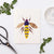 The BUMBLEBEE CARD by PETAL PEOPLE PRESS features a charming bee crafted as botanical art, artfully composed of pressed flowers and leaves on a white background. It showcases yellow petals for the body, purple blooms for the stripes and head, and delicate leaves for the wings and legs—a delightful addition to any floral card collection.