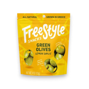 A yellow packet of FREESTYLE - LEMON GARLIC GREEN OLIVES from FREESTYLE SNACKS, featuring green olives flavored with extra virgin olive oil. The packaging highlights the "all-natural" ingredients and notes that the olives are "grown in Greece." Weighing 4 oz (113g), the pack showcases images of green olives alongside phrases such as "pitted & unpasteurized" and "healthy snacking on the go.