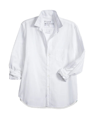 The EILEEN Relaxed Button-Up by Frank & Eileen features a white chambray fabric with long sleeves, a chest pocket, and bust-flattering buttons. The collar displays "Frank & Eileen EST. 1947," while the sleeves are slightly rolled for a casual look.