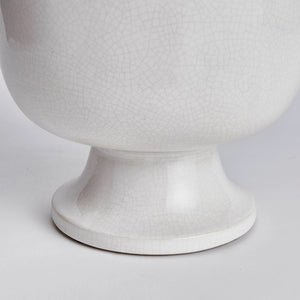 The ALBIE FOOTED CACHEPOT by NAPA HOME AND GARDEN is a white, ceramic, round planter with a simple, smooth design. It features a wide, shallow bowl on top that sits on a short, broad pedestal base. Finished with a shiny white glaze and slight crackled texture, it makes for a beautiful centerpiece while retaining its minimalist appeal.