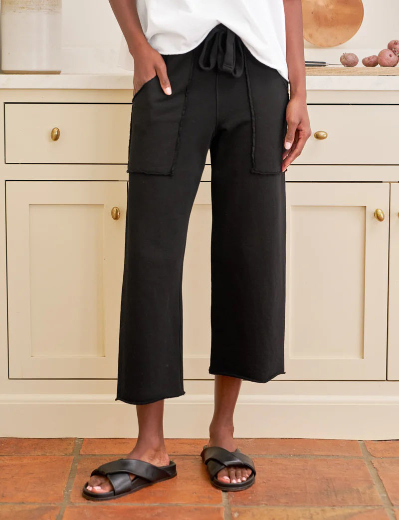 The FRANK &amp; EILEEN Penny Patch Pocket Sweatpant in black features a cropped wide-leg style, elastic drawstring waistband, and large front patch pockets, crafted from cozy triple fleece and shown flat on a white background.