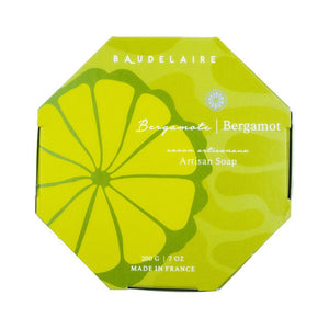 A round, yellow bar of French-milled soap with the text "BAUDELAIRE 7oz" embossed in the center. Enriched with shea butter, this smooth, shiny bergamot soap boasts a simple and elegant circular design.