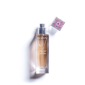 A clear 30ml ROSE ET MARIUS - A ROSE WINE UNDER THE ARBOR Eau de Parfum spray bottle, with a pink and white patterned cap beside it, rests on a white background. Soft light casts a gentle shadow to the left.