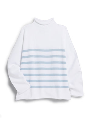 A woman with long dark hair wears a Monterey Rolled Funnel Neck Stripe Sweater from FRANK & EILEEN. The sweater, made of machine-washable Italian cotton, features light gray stripes on the back. She layers it over a white shirt and gazes to the side in a softly lit neutrally toned room.