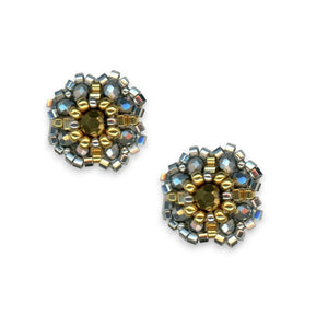 The MIGUEL ASES - BEADED MIYUKI STUD EARRINGS from MIGUEL ASES, INC. are intricately designed, featuring circular patterns and a central 14K gold-fill gem. Handcrafted in America, these earrings are adorned with metallic and small square beads in varying shades that form a beautiful floral-like structure.