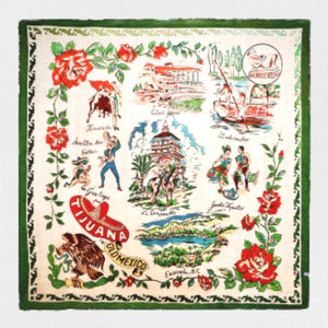 Introducing the ELA SCARF by TALKING WALLS: a square vintage piece crafted from high-resolution printed silk/modal fabric. This stunning accessory features colorful illustrations and text depicting landmarks and activities in Tijuana, Mexico. The border showcases a green pattern adorned with red roses, while the central illustrations include dancers, cowboys, and scenic buildings.