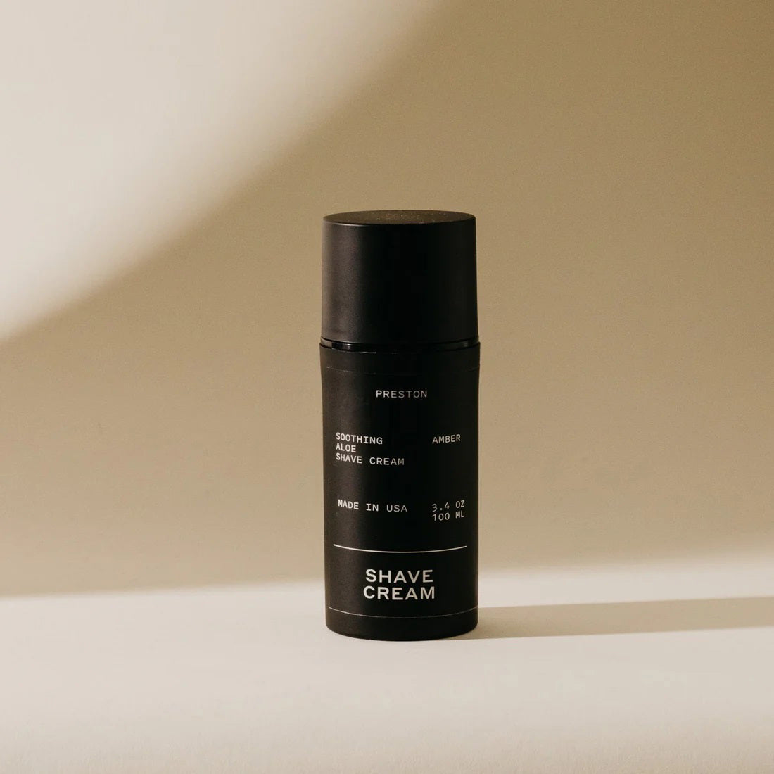 A black cylindrical bottle of PRESTON - SHAVE CREAM with a matte finish, labeled &quot;Preston&quot; at the top. The label reads, &quot;Soothing Aloe Shave Cream,&quot; &quot;Leather,&quot; and &quot;Made in USA.&quot; Featuring a cruelty-free formula designed for razor burn prevention, the bottle has a sleek design against a neutral background.