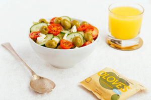 A sealed beige snack pack of POSHI brand, labeled "OLOVES - LEMON & ROSEMARY." The pack features an illustration of green olives. Text on the pack highlights it as a "Low Calorie Snack" and mentions 50 million packs sold. Pack size is 30g (1.1 oz).